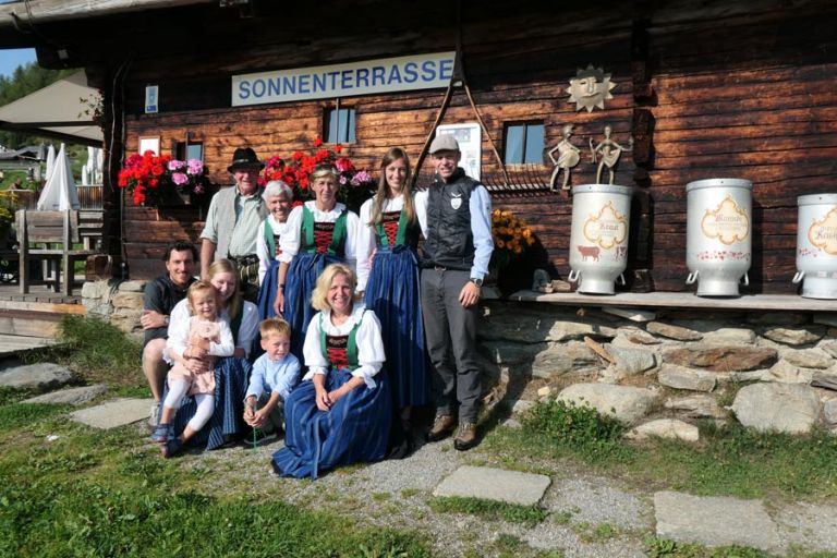 Familie steht vor Almhütte mit Tracht